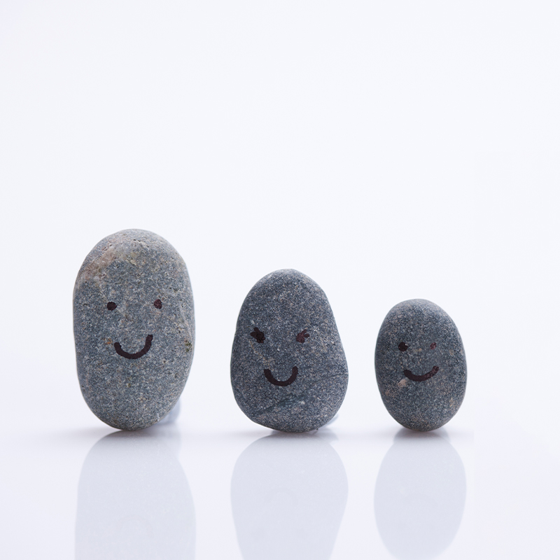 눈, 코, 입이 그려진 서로 다른 모양의 3개의 돌들이 웃고 있다.